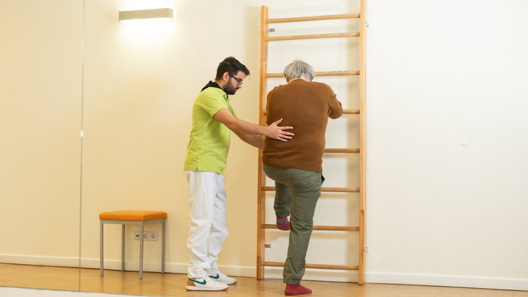 Patient macht Übung an Sprossenwand - Immanuel Therapiewelt - Ergotherapie - Physiotherapie